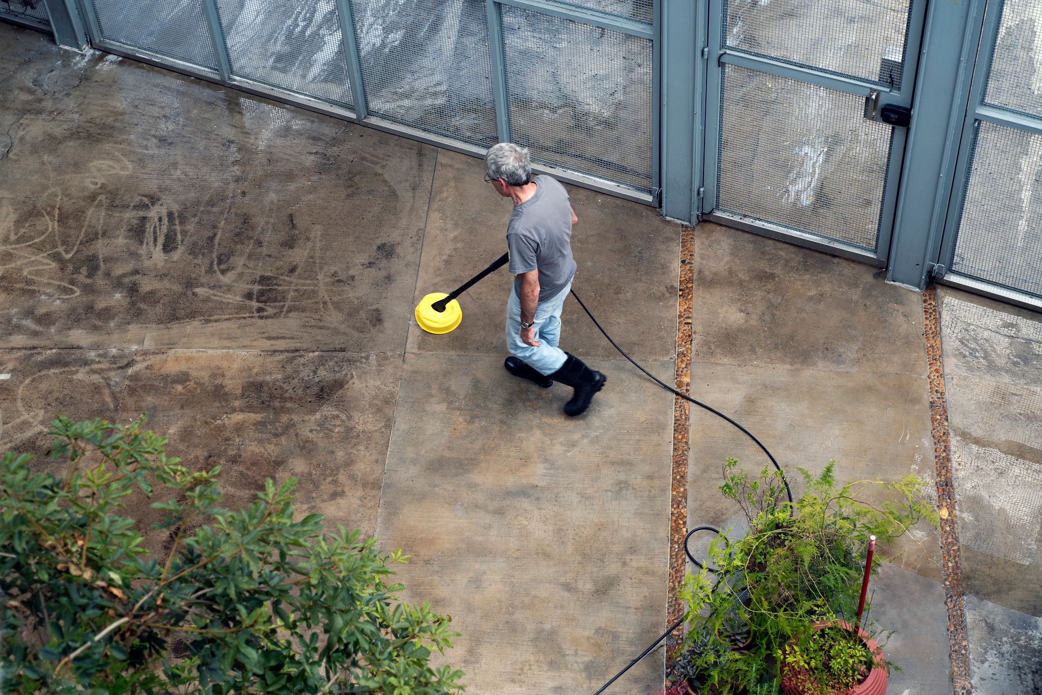 Man cleaning pavement with power washer